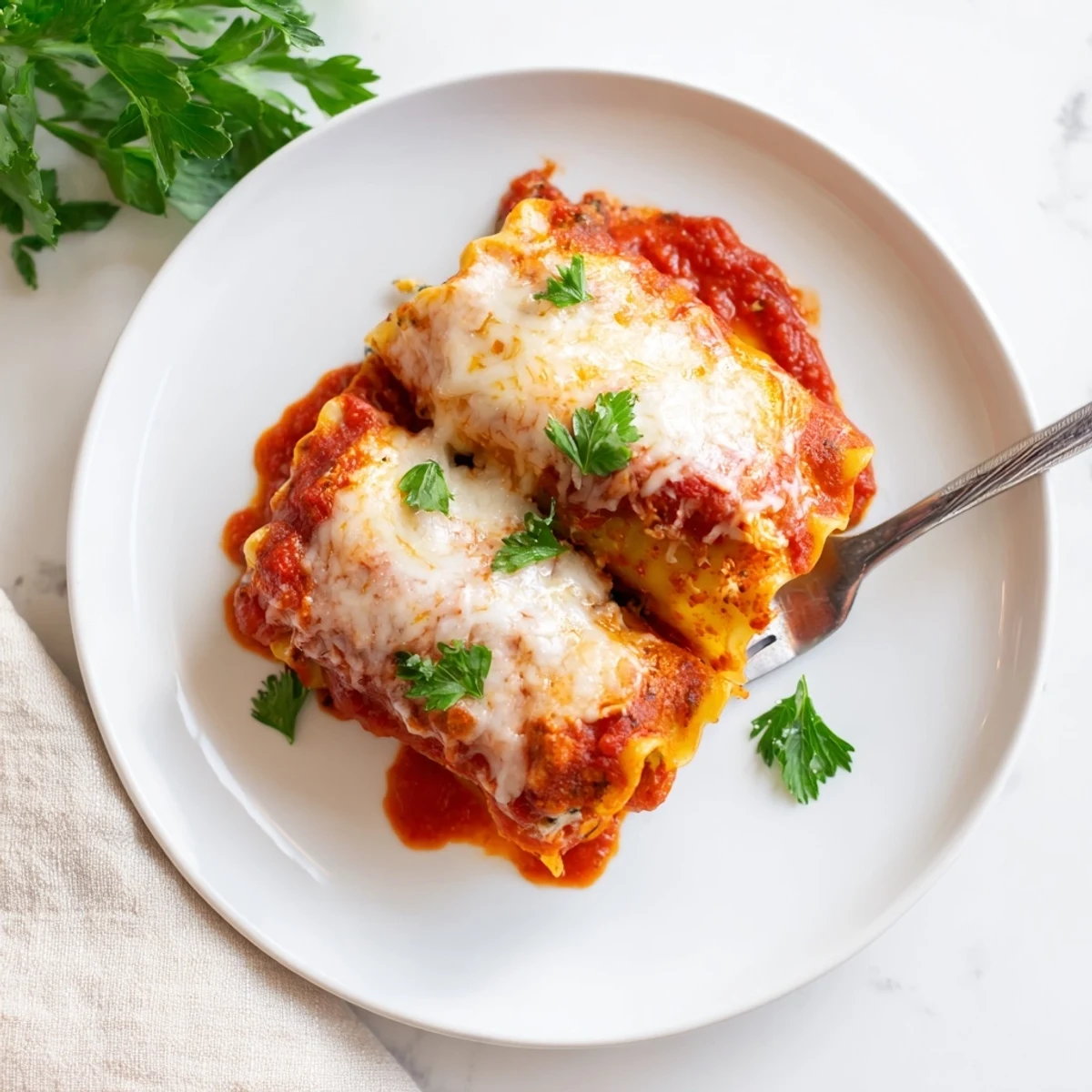 A close-up shows rolled lasagna noodles filled with creamy chicken and spinach, topped with grated Parmesan and fresh parsley.