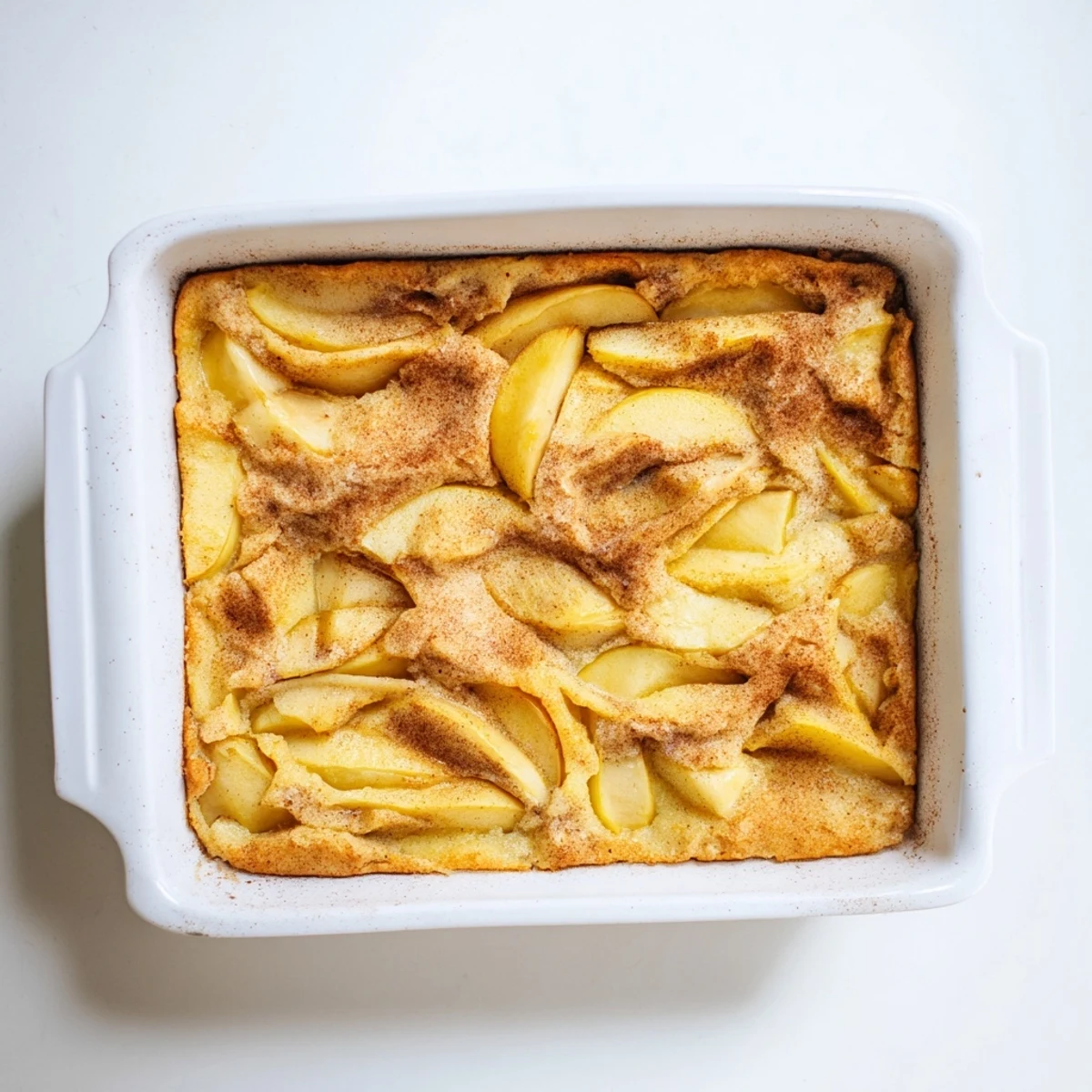 Freshly baked Baked Apple Cake with cinnamon sugar topping, golden edges, and tender apple slices in a cozy, casserole-style breakfast presentation.