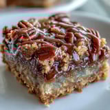 Crumb-topped turtle bars on a white plate with a glass of milk.