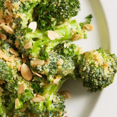 Fresh Garlic Parmesan Broccoli Salad with blanched florets, red onion, and creamy dressing garnished with almonds and parsley.