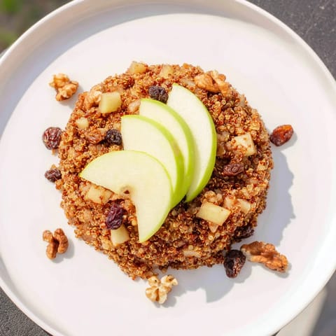 Close-up of a vibrant apple cinnamon quinoa bowl, enticing with cinnamon aroma, topped with crunchy walnuts.