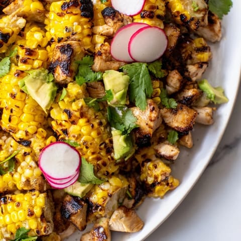 Savory roasted corn and grilled chicken chopped salad with creamy avocado and crisp radishes, tossed in a zesty lime dressing for a fresh, light meal.  