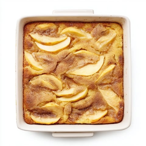 Warm slice of Baked Apple Cake served on a plate, dusted with powdered sugar, alongside a cup of coffee for a comforting brunch.