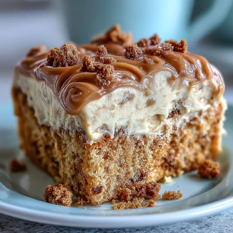 A golden slice of Decadent Baked Biscoff Cake reveals tender vanilla sponge studded with crunchy Biscoff pieces.