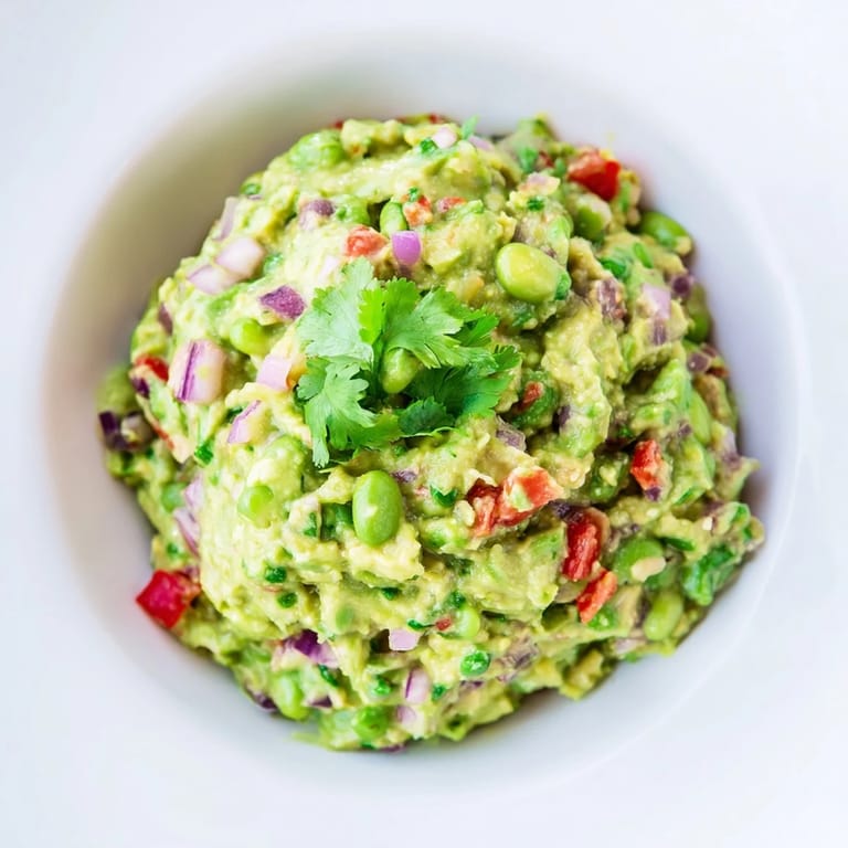 Freshly made edamame guacamole boasting vibrant green color, perfect with tortilla chips for a snack.