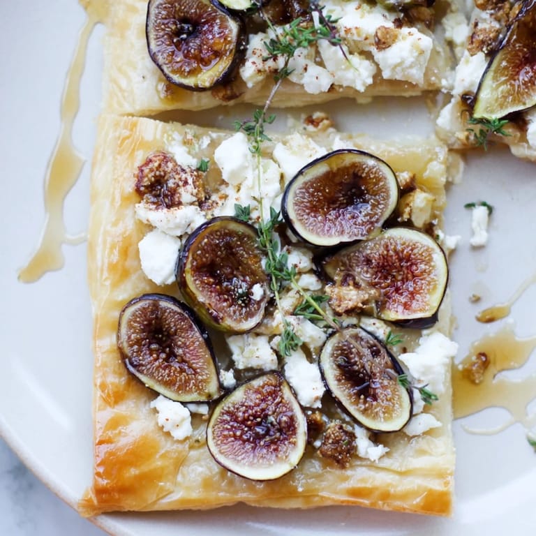 Close-up of a warm puff pastry truffle pizza with honey, figs, and creamy goat cheese.