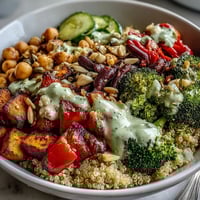 Close-up of a vibrant Meal Prep Week-Long Power Bowl, featuring fluffy quinoa topped with roasted sweet potatoes and broccoli, creamy chickpeas, and a drizzle of tahini dressing.