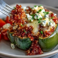 Golden-brown Quinoa Stuffed Bell Peppers, topped with melted goat cheese, ready to serve.